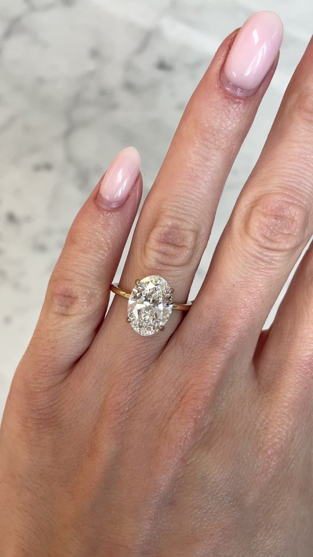 on hand of 4ct oval cut diamond in our whisper thin yellow gold with platinum prongs