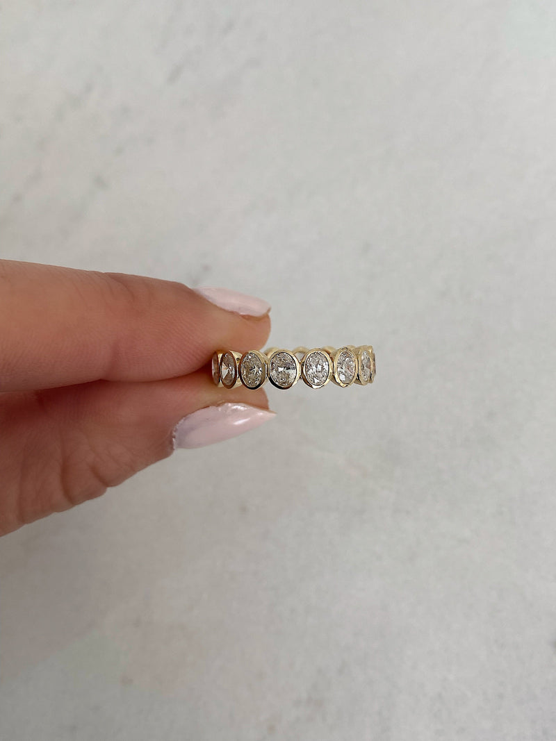 Bridal Wedding Bands Petite Oval Bezel Eternity Band model holding ring to show detail
