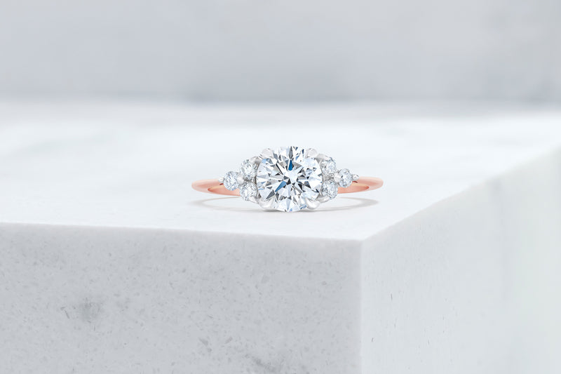 Tribeca VOW by Ring Concierge round with trio side stones engagement ring in rose gold. 33281407647832